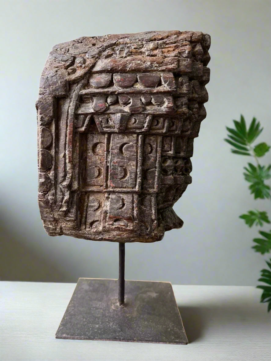 An old teakwood vintage pillar candle base with ethnic motifs hand-carved, displayed on a metal stand.
