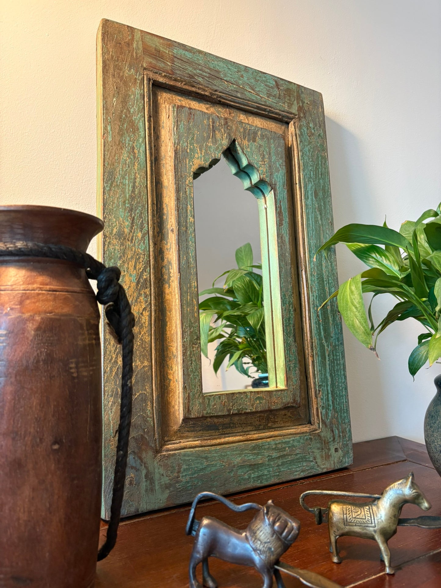 Vintage-style mirror with wooden frame on a surface with decorative items
