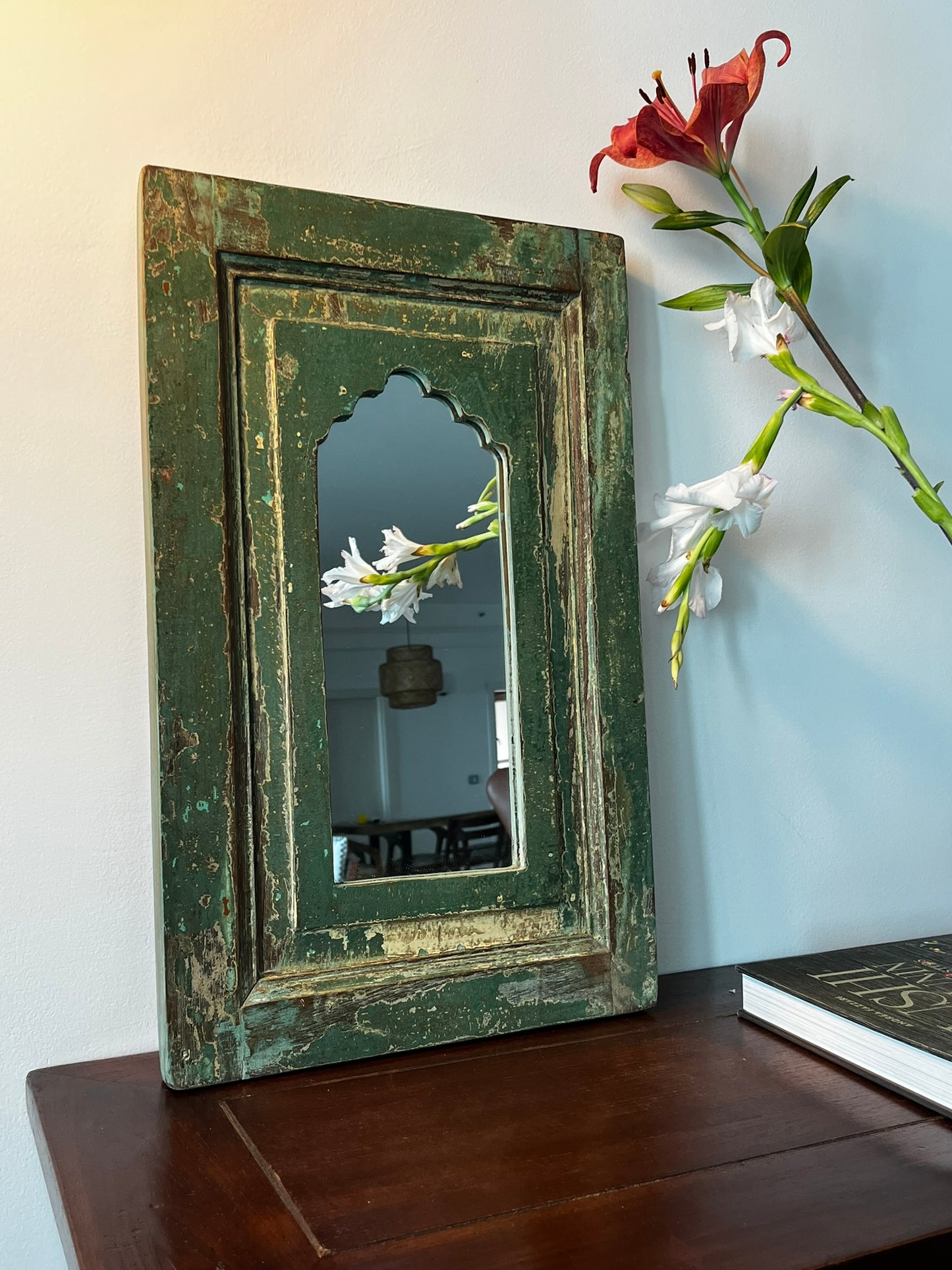 A vintage teakwood mirror with a green frame, hanging on a wall.