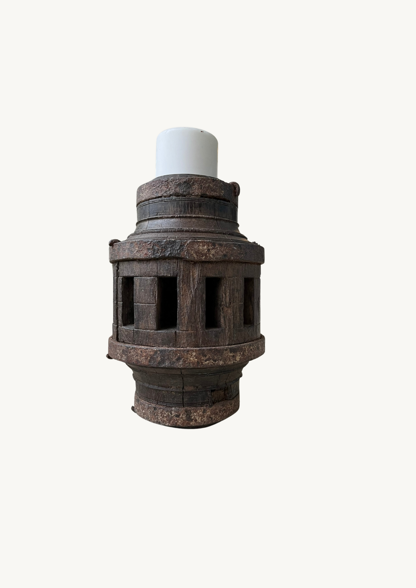 A candle holder made from an old wooden carriage wheel hub with a weathered texture and a white candle on top.