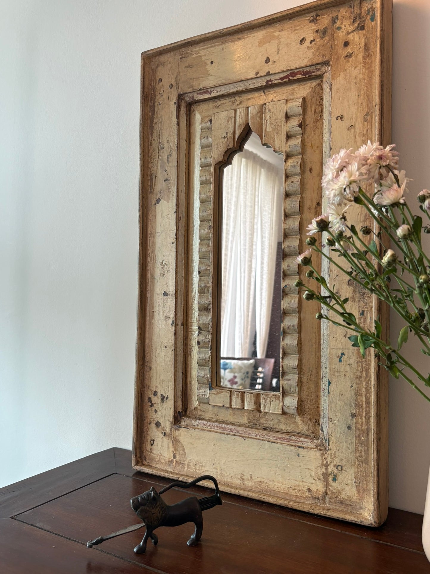 Decorative antique mirror with a rustic wooden frame on a table.