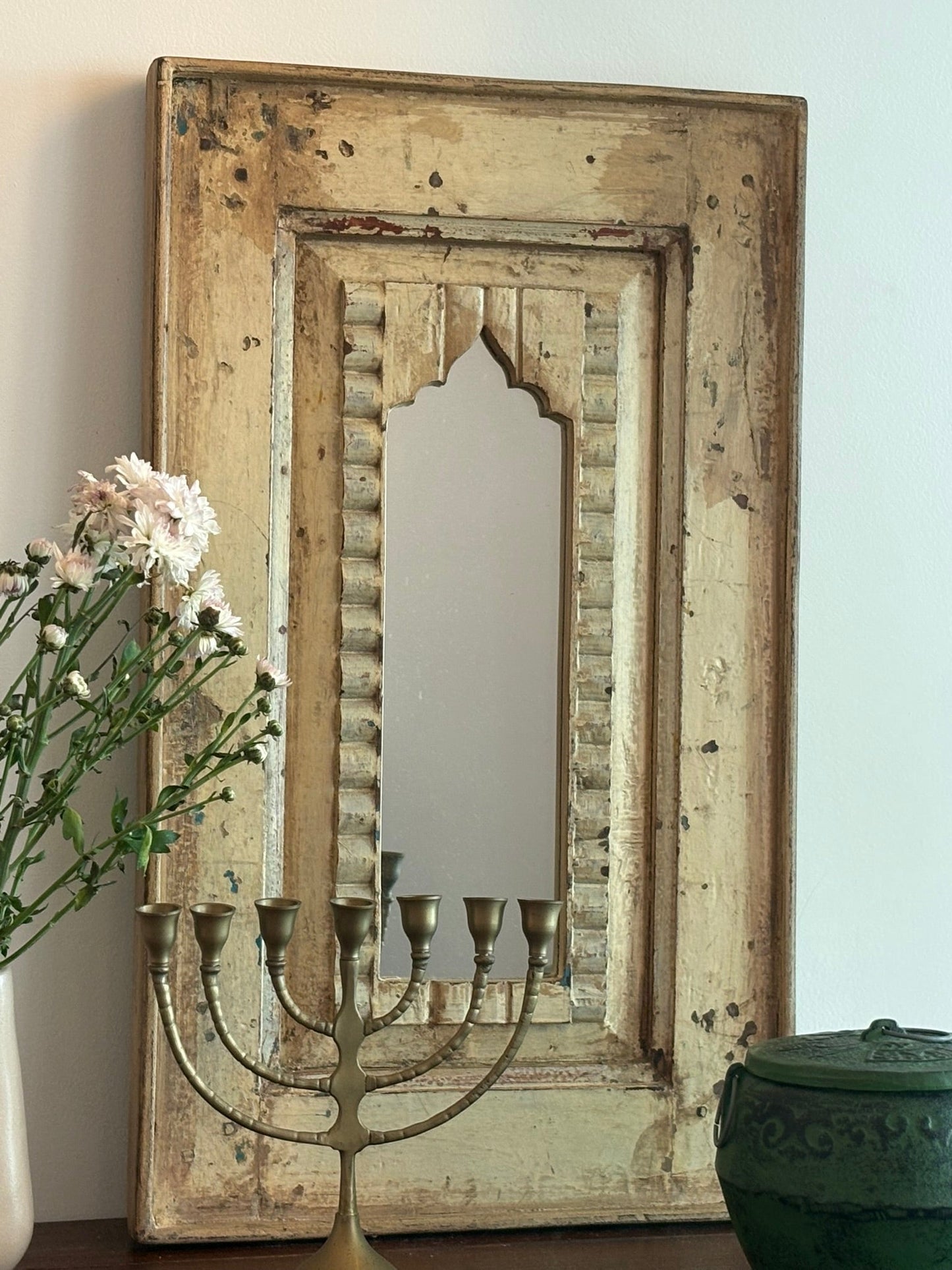 Decorative mirror with wooden frame and candle holder on a wall.