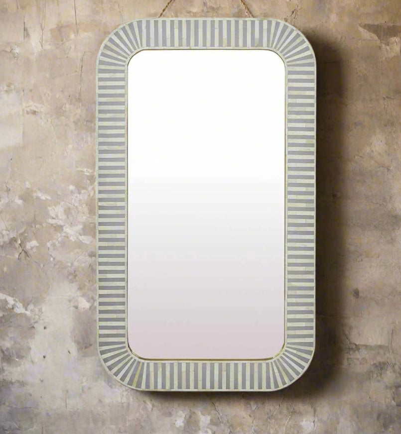 A rectangular mirror with striped inlay work in off white and gray tones along the border, mounted on a wall.