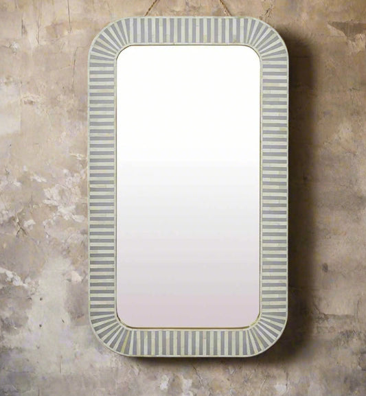 A rectangular mirror with striped inlay work in off white and gray tones along the border, mounted on a wall.