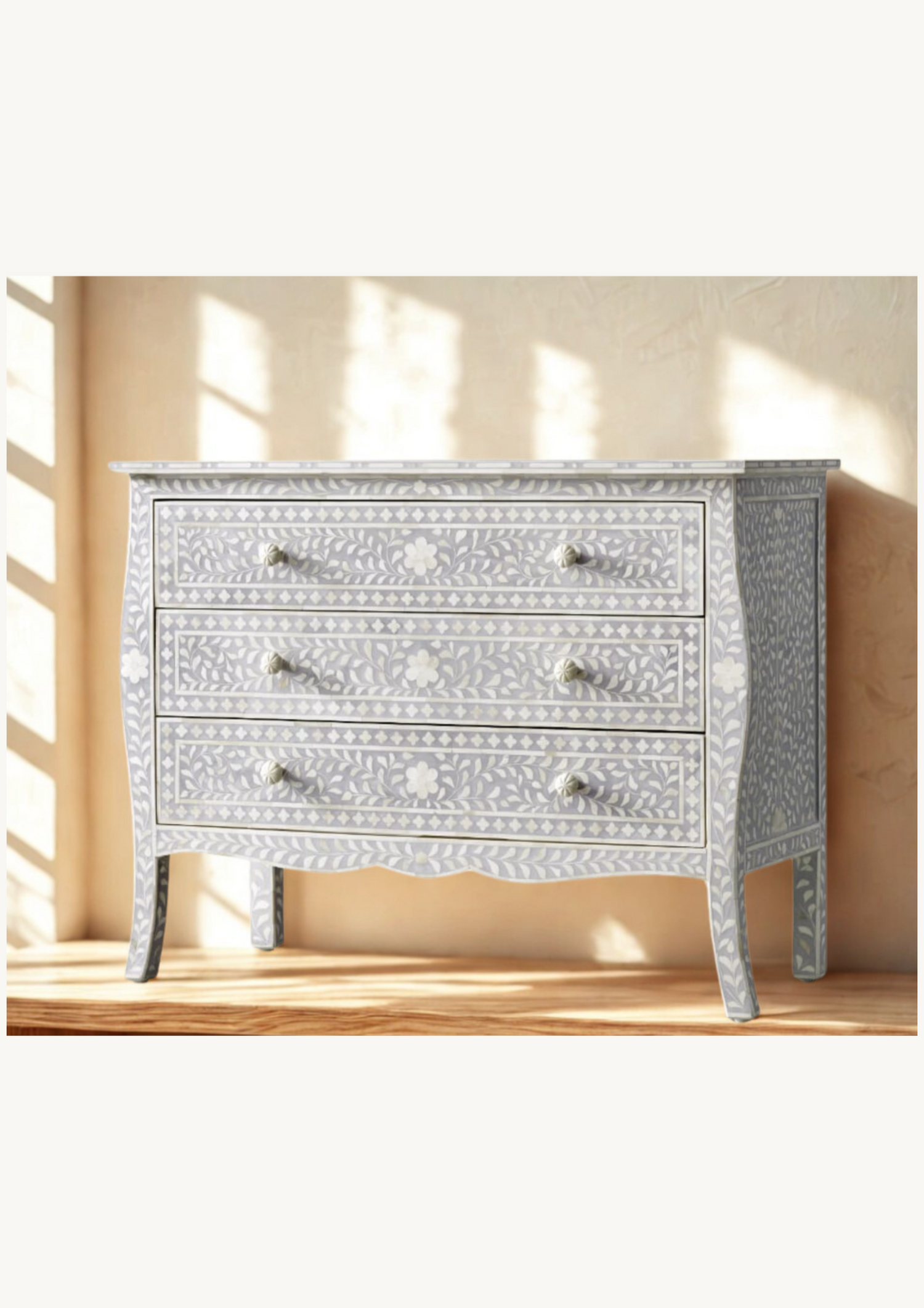 Decorative grey chest of drawers with intricate inlay patterns on a wooden floor.
