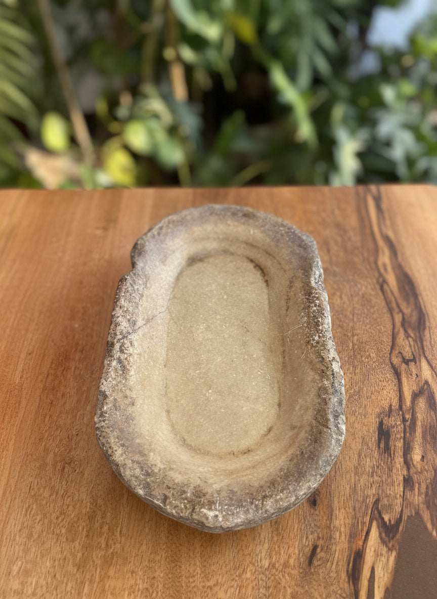 Antique marble bowl on a wooden surface with a natural background