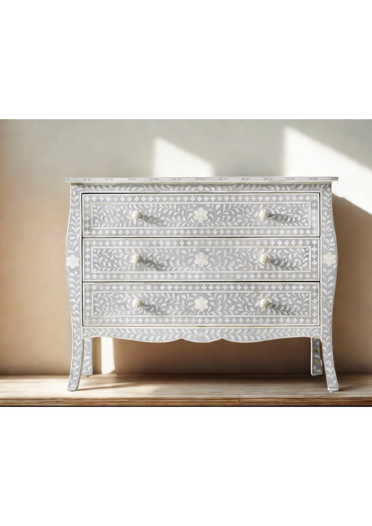 White decorative dresser with intricate inlay patterns on a wooden surface.