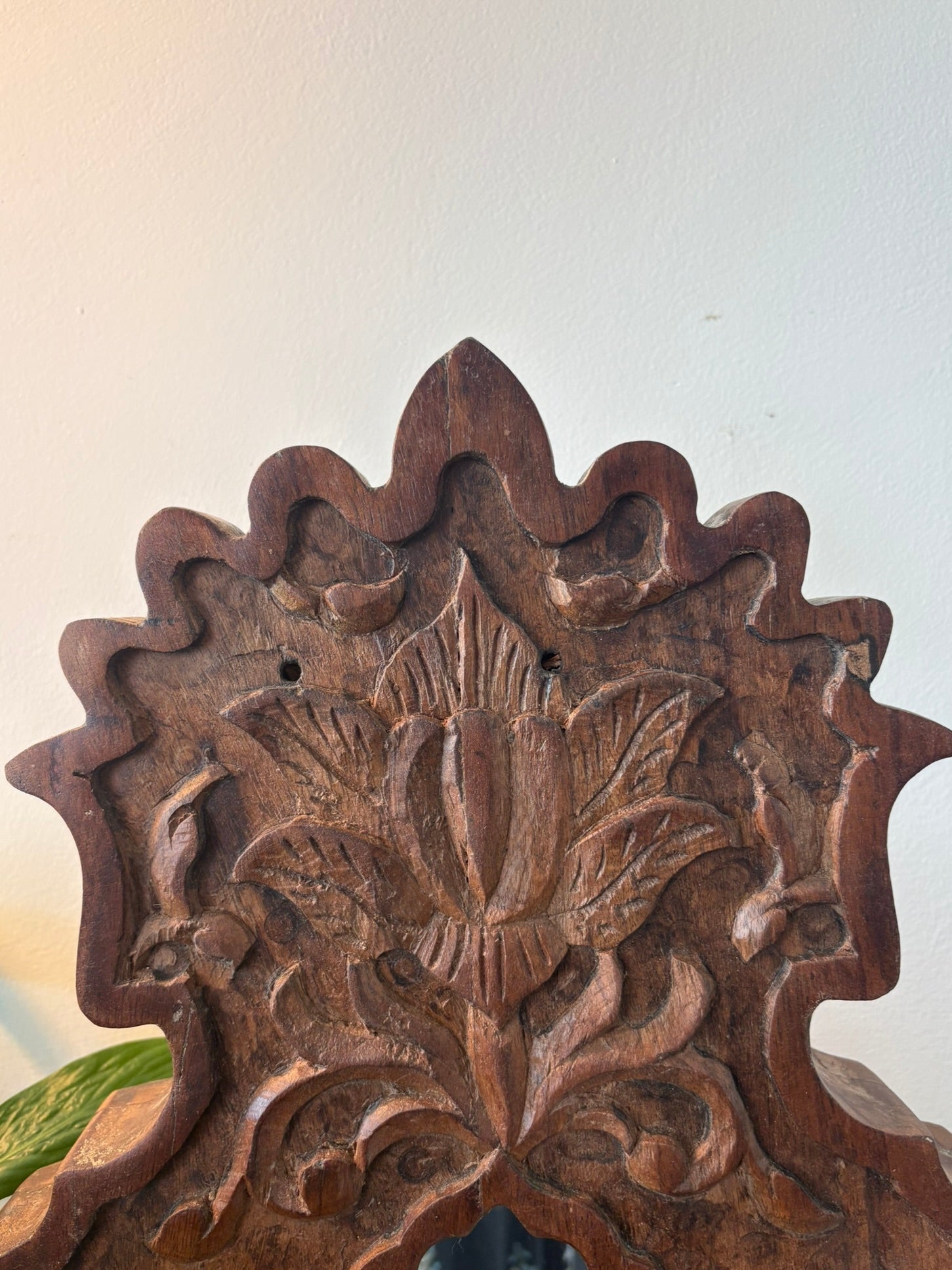 Wooden decorative mirror with floral carvings on a plain background