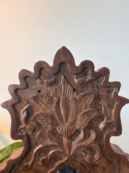 Wooden decorative mirror with floral carvings on a plain background