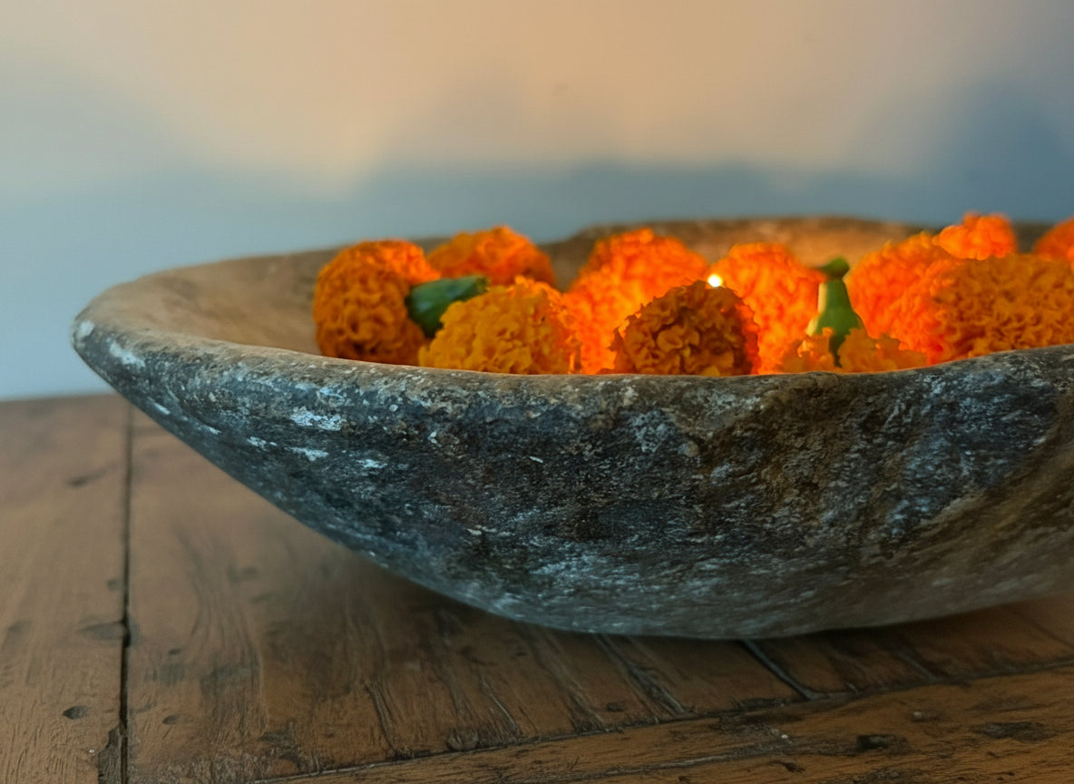 Decorative stone bowl with small orange flowers on a dark surface