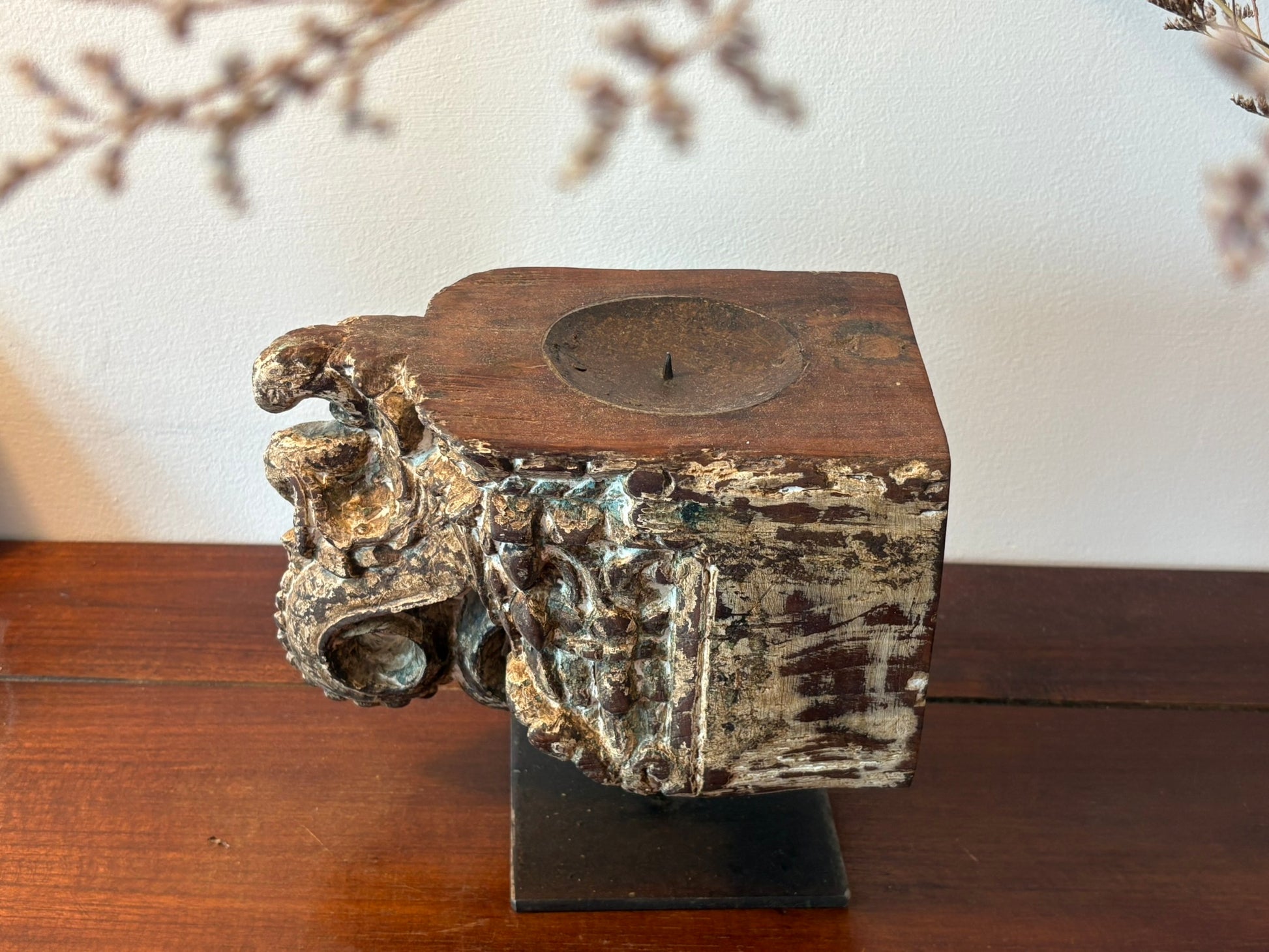 Decorative candle holder with rustic metal and wooden design on a wooden surface.