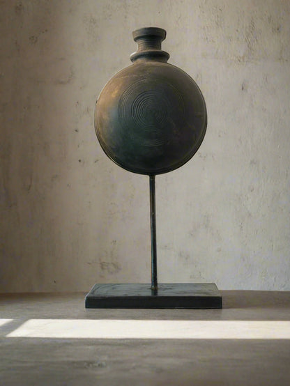 Handmade black pot on a stand against a neutral background