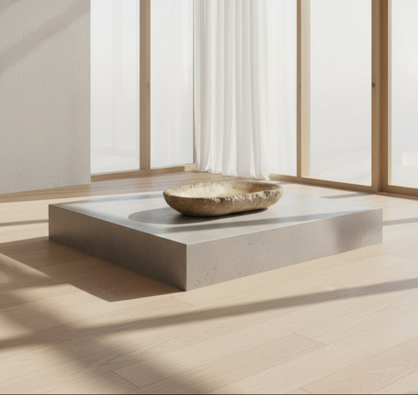 Antique marble bowl on a platform in a minimalistic room with large windows