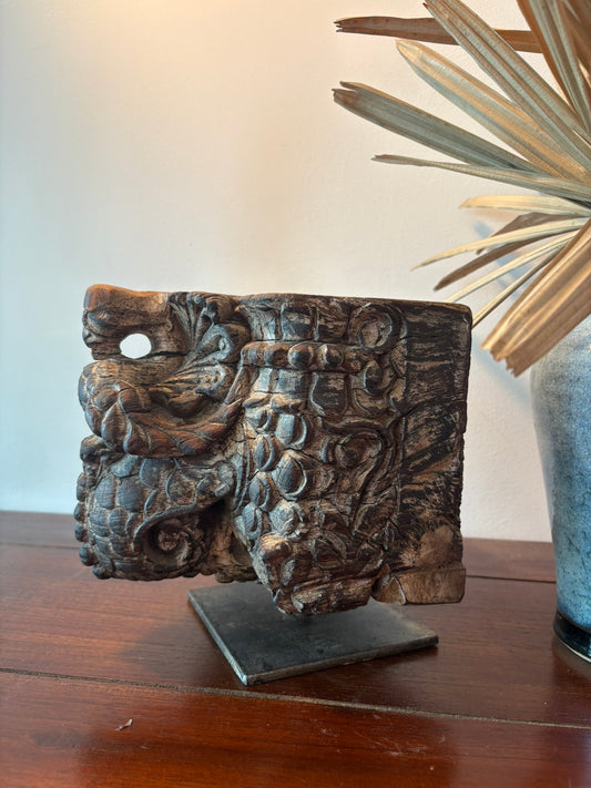 Decorative wooden candle  holder on a stand with a plant in the background