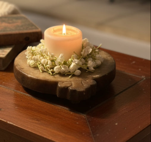 Candle on a marble holder with flowers on a wooden surface
