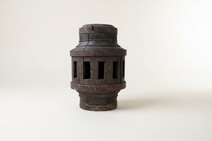 A vintage pulley candle stand made from weathered wood with a cylindrical shape and cut-out designs on the sides.