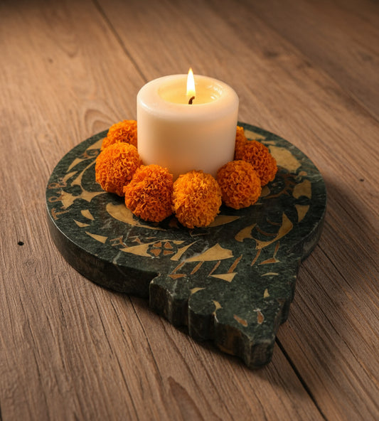 Candle in a decorative stone holder with orange flowers on a light surface