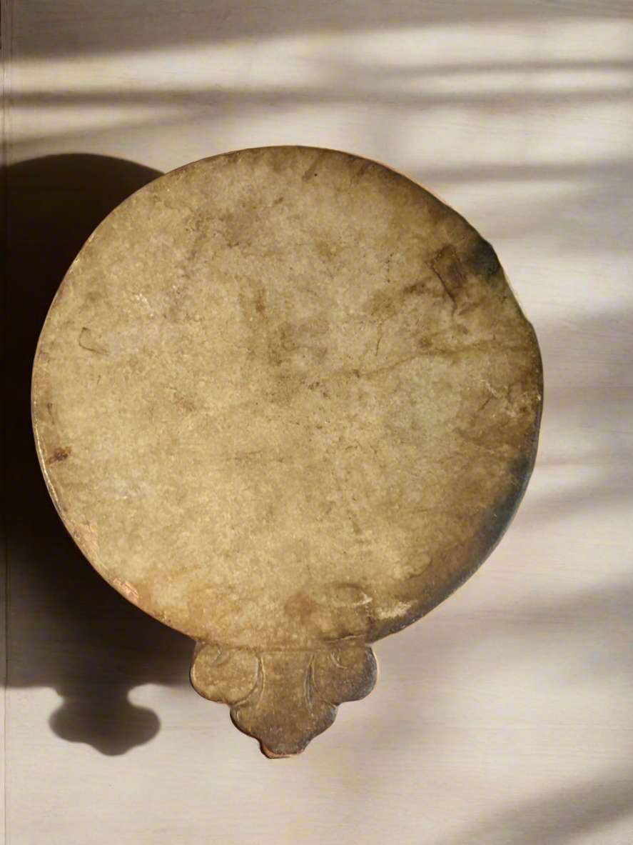 Round stone object with decorative edge on a light background