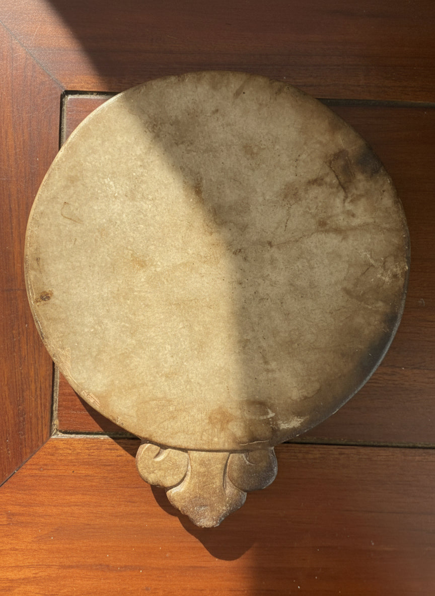 Round stone object with a decorative base on a wooden surface