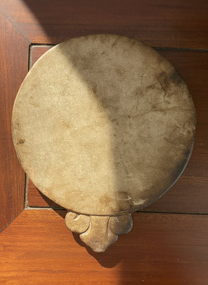 Round stone object with a decorative base on a wooden surface