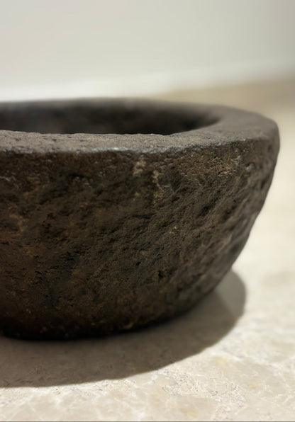 Close-up of a dark stone bowl on a light surface