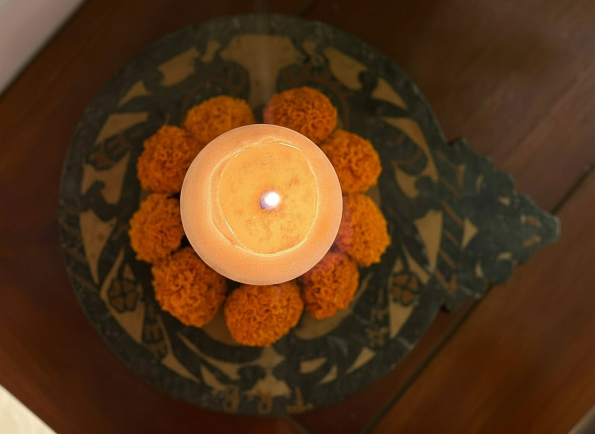 Candle in a decorative antique marble holder with marigold flowers on a wooden surface