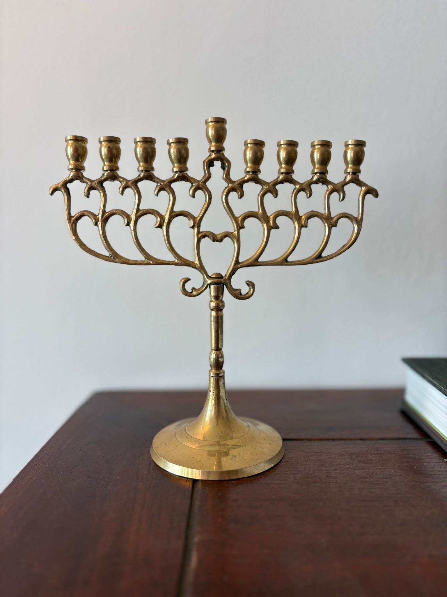 A traditional nine-branch menorah made of brass, displayed on a wooden surface.