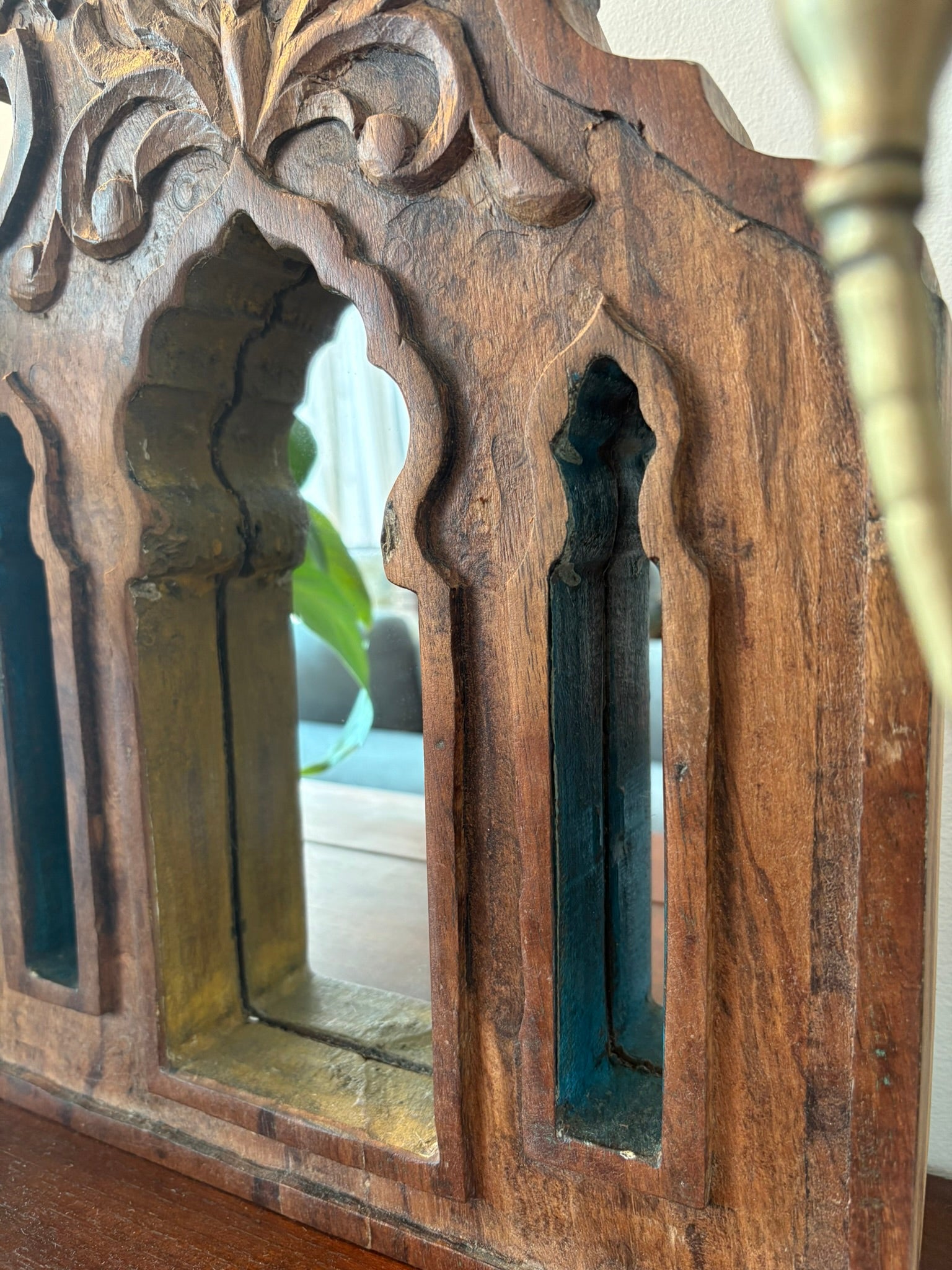 Decorative wooden mirror with intricate carvings and blue painted panels.