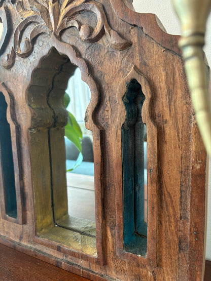 Decorative wooden mirror with intricate carvings and blue painted panels.