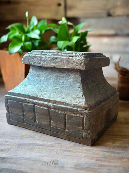 Decorative wooden pillar base candle stand on a wooden floor.