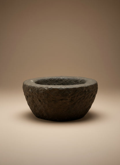 Dark stone antique bowl on a beige background