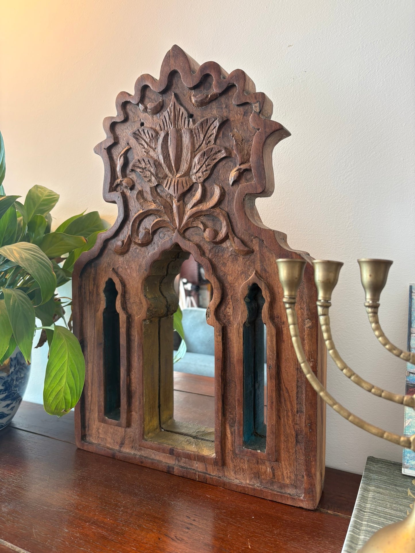 Wooden decorative mirror with intricate carvings on a wooden surface.