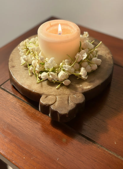 Candle in a decorative holder with flowers on a wooden surface