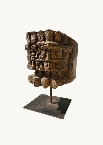 A vintage pillar candle base made of old teakwood, featuring ethnic motifs and hand-carved details, displayed on a metal stand.