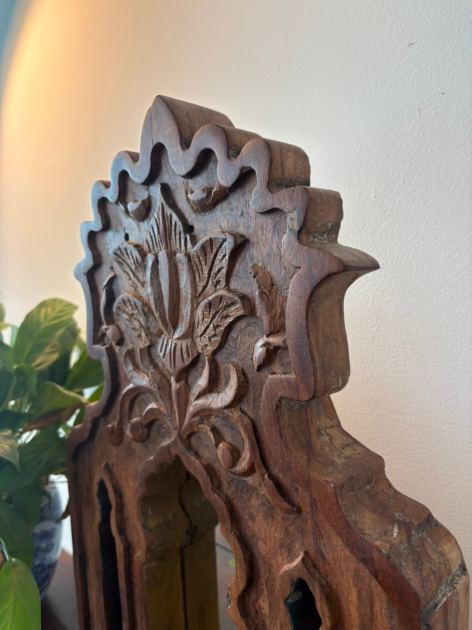 Wooden decorative mirror with intricate carvings on a plain background